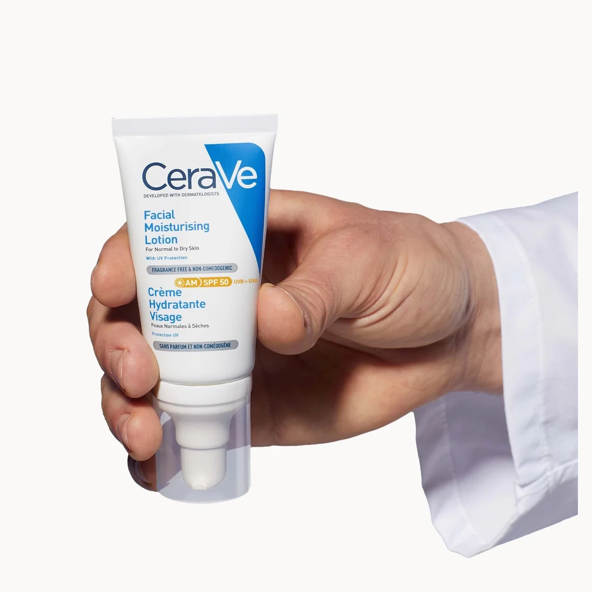 A hand holding a tube of CeraVe Facial Moisturising Lotion SPF 30, with a white lab coat sleeve visible on the right, against a plain white background.