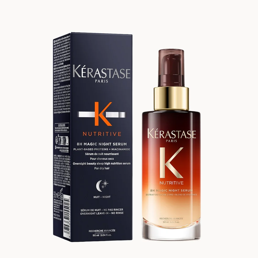 Kérastase Paris Bi-Magic Night Serum in a dark navy blue box next to the amber glass spray bottle with a gold collar and dark brown pump, on a light gray background.