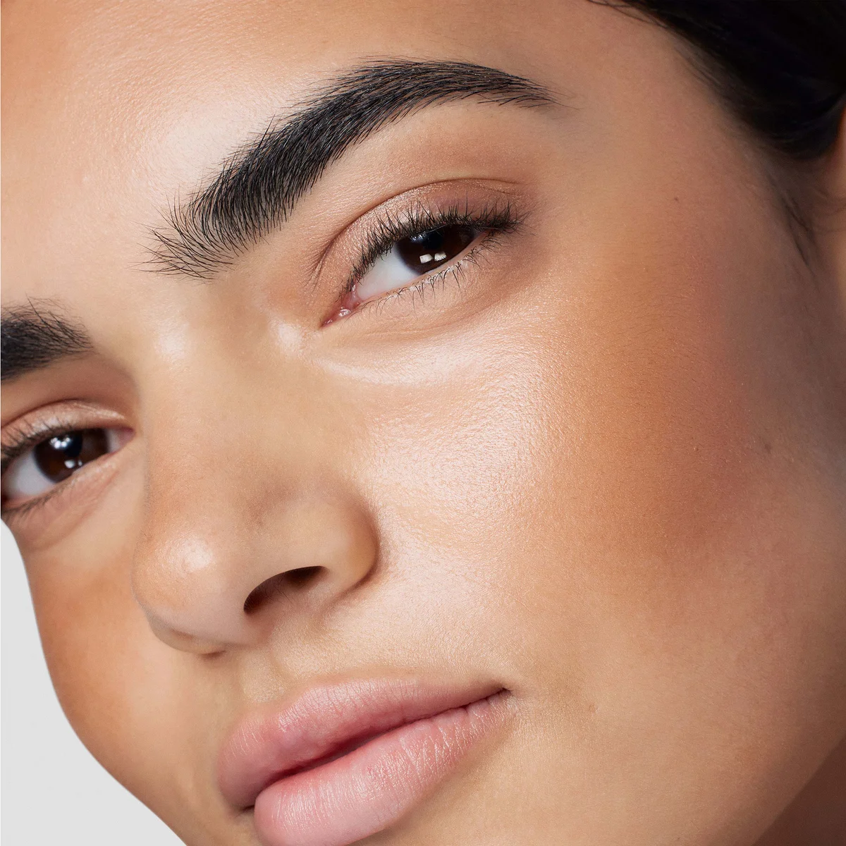 Close-up of a person's face wearing Laura Mercier Tinted Moisturiser Bronzer 03 Sunbeam