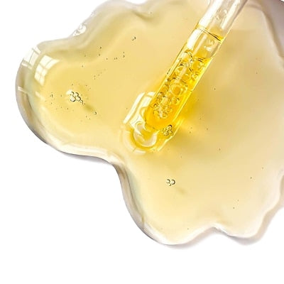 Close-up of a dropper with yellow liquid on a white background