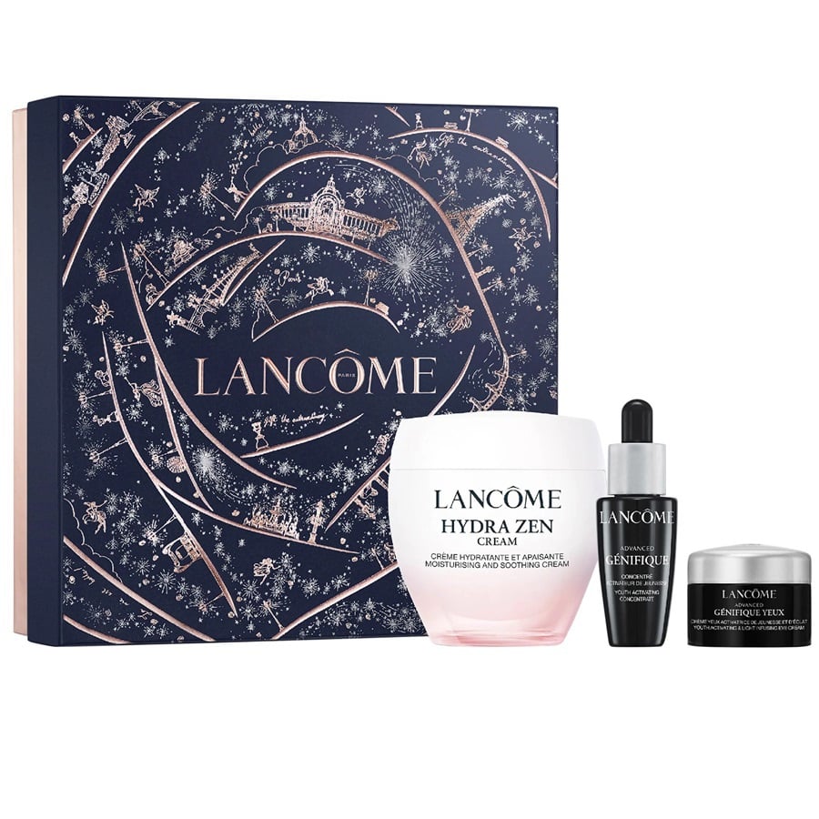 Lancôme gift set featuring a large navy blue illustrated box with rose-gold line art and the brand name, alongside three skincare products: a Hydra Zen Cream jar, a Genifique serum dropper bottle, and a Conéction cream jar, all on a white background.