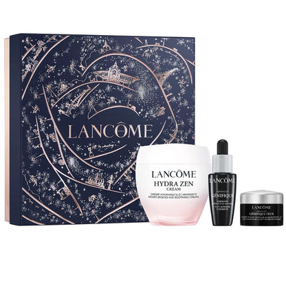 Lancôme gift set featuring a large navy blue illustrated box with rose-gold line art and the brand name, alongside three skincare products: a Hydra Zen Cream jar, a Genifique serum dropper bottle, and a Conéction cream jar, all on a white background.