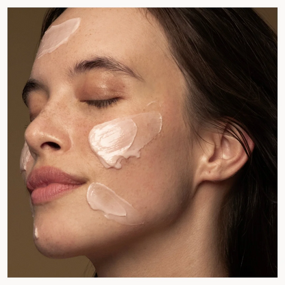Close-up of a woman's face with cosmetic cream applied to her cheeks.
