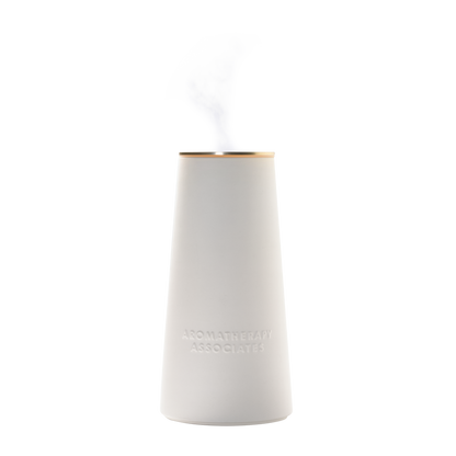 White ceramic aromatherapy diffuser with gold rim on a white background
