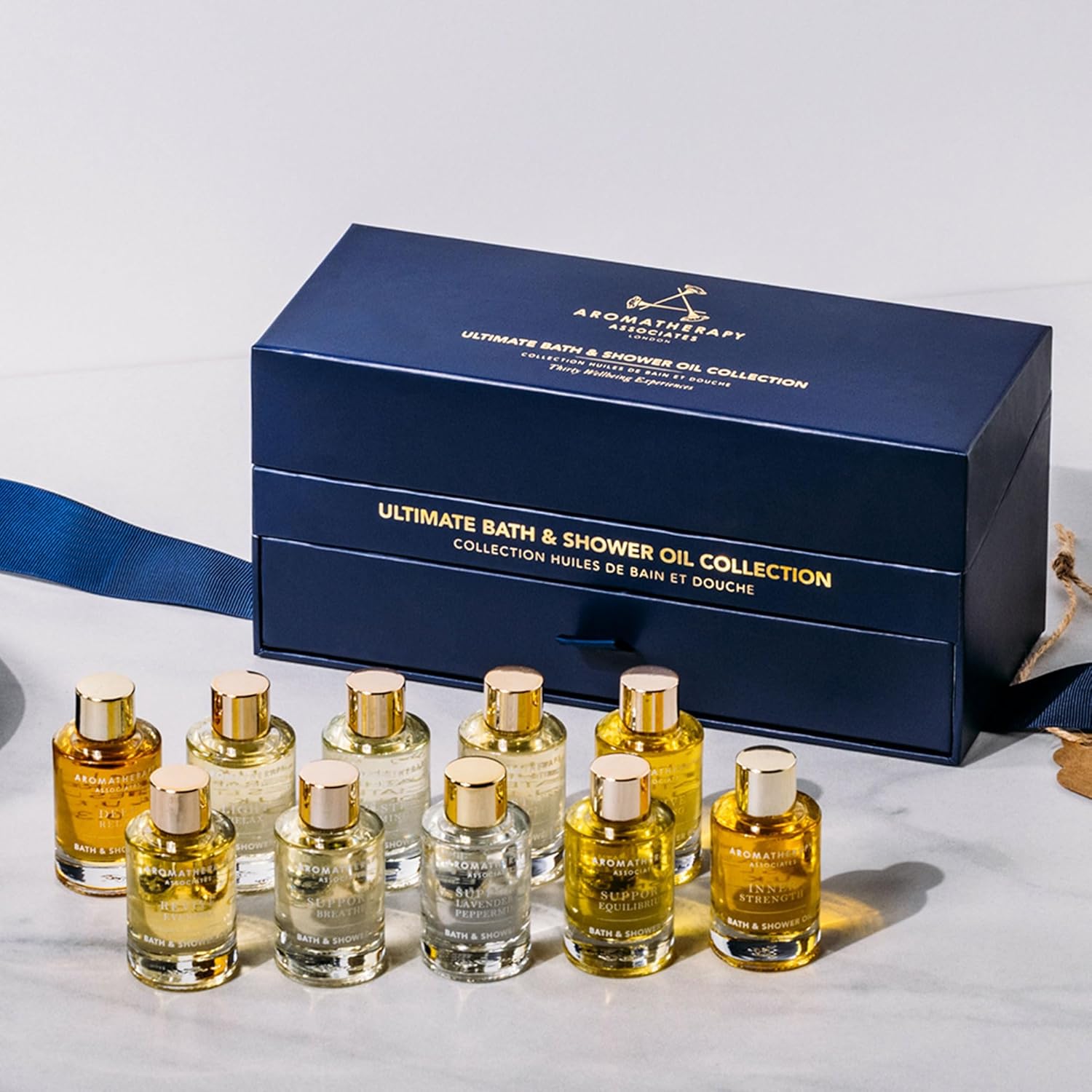 Collection of bath and shower oil bottles with a blue packaging box on a light gray background