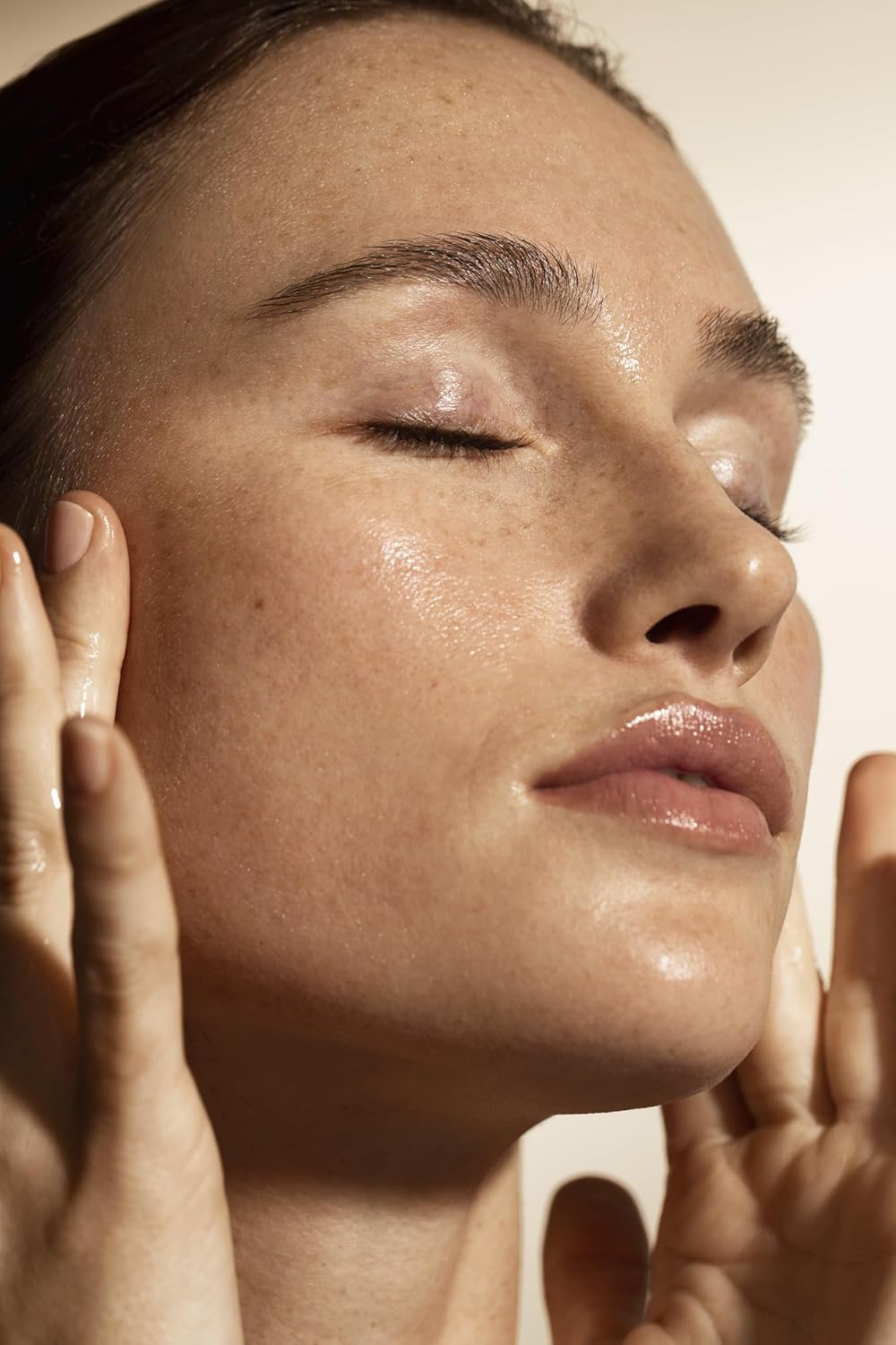 Close-up of a person with their eyes closed, touching their face.