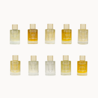 Set of 10 small Aromatherapy Associates Ultimate Wellbeing Bath & Shower Oil bottles arranged in two rows on a white background