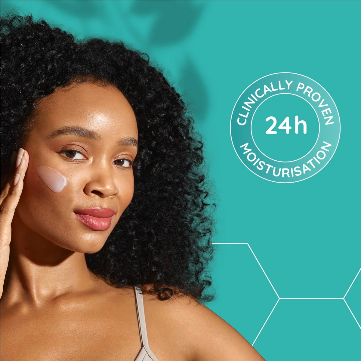 A woman with curly black hair applies a light cream product to her cheek against a teal background with white text reading 'Clinically Proven 24h Moisturisation'.