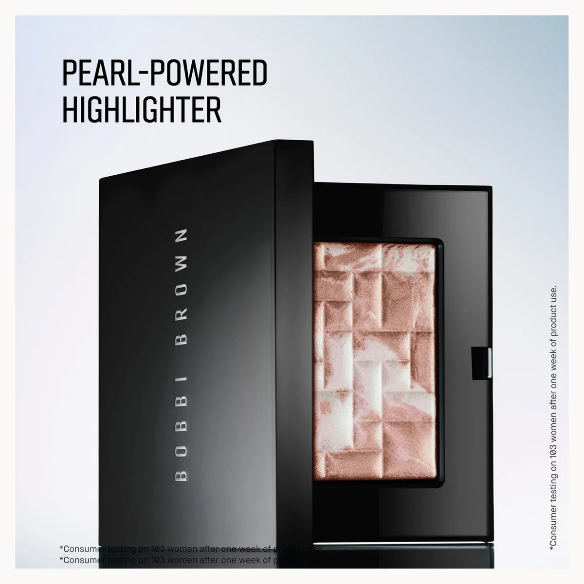 Bobbi Brown Pearl-Powered Highlighter in a black compact, shown open with the pressed powder visible. The packaging features the Bobbi Brown brand name vertically on the side.
