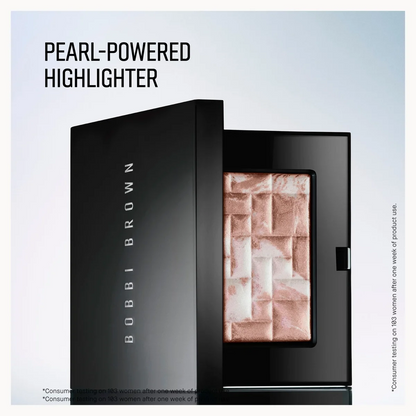 Bobbi Brown Pearl-Powered Highlighter in a black compact, shown open with the pressed powder visible. The packaging features the Bobbi Brown brand name vertically on the side.