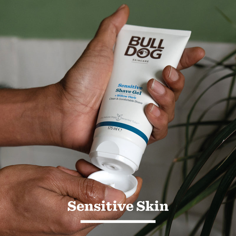 Hand holding a tube of Bulldog Sensitive Shave Gel with a blurred background