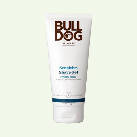 A white squeeze tube of Bulldog Skincare Sensitive Shave Gel with Willow Herb, featuring brown and blue text, centered on a pale green background.