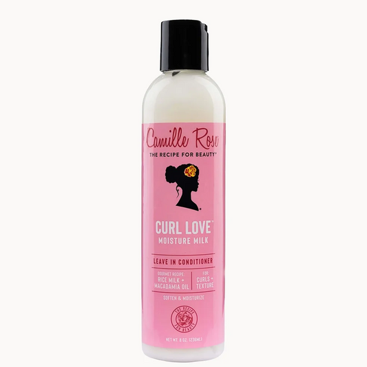 A bottle of Camille Rose Curl Love Moisture Milk leave-in conditioner, featuring a pink label and black cap on a light off-white background.