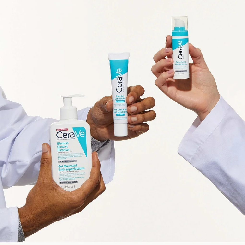 Three hands wearing white lab coats hold CeraVe skincare products against a clean white background: a pump bottle, a tube, and a small bottle.