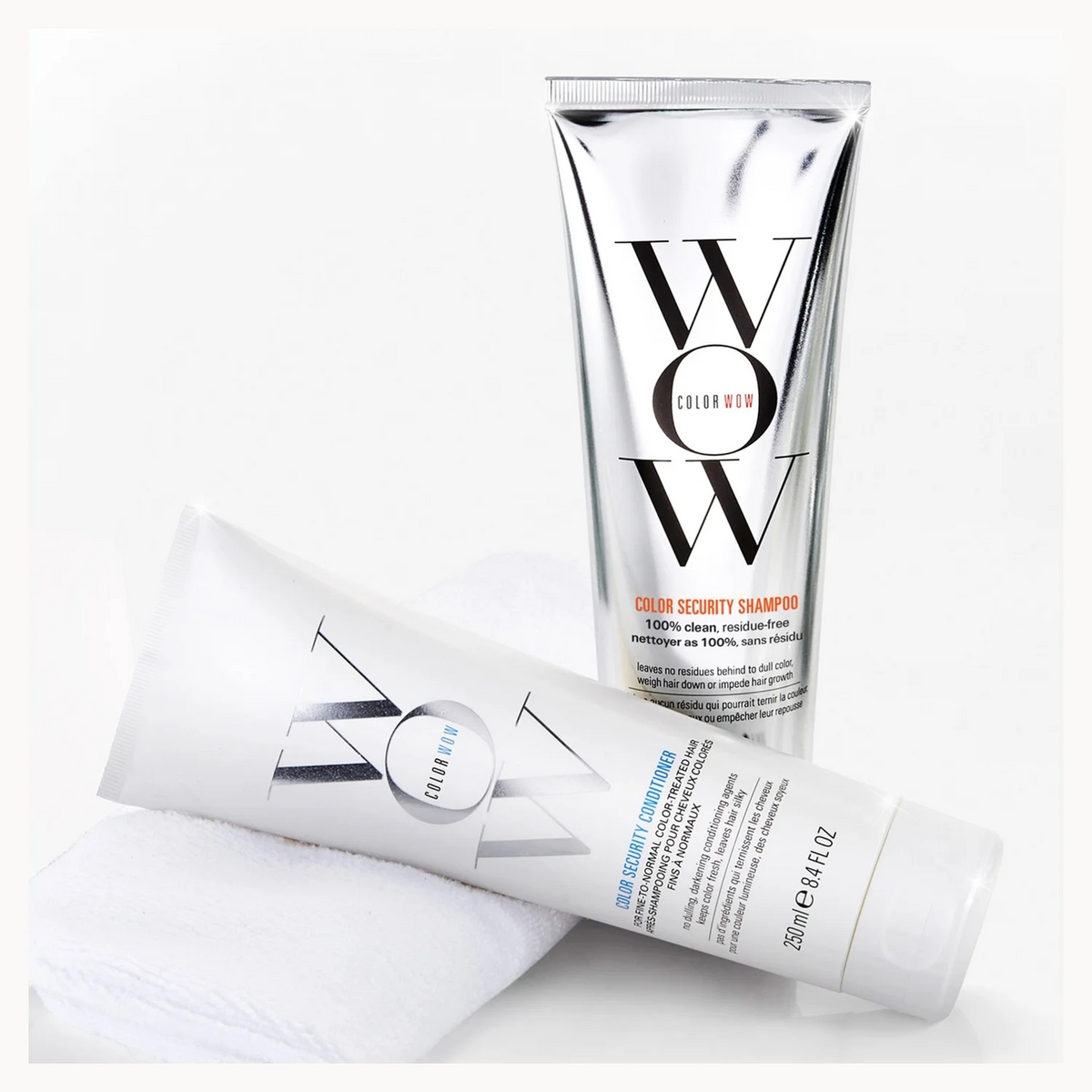 A hair care set featuring a tall silver tube of WOW Clear Secretory Shampoo and a white tube of WOW Clear Bond Care Conditioner, arranged on a white background with a folded white towel.