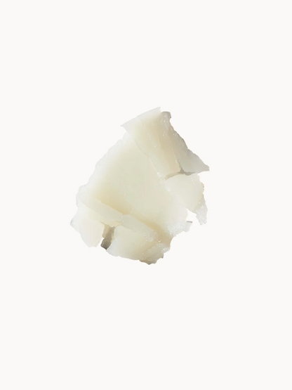 A small irregular piece of off-white wax or solid cosmetic material on a plain white background.