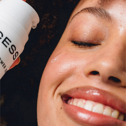 Close-up of a person applying sunscreen to their face with a bottle labeled 'Cure Essentiel'.