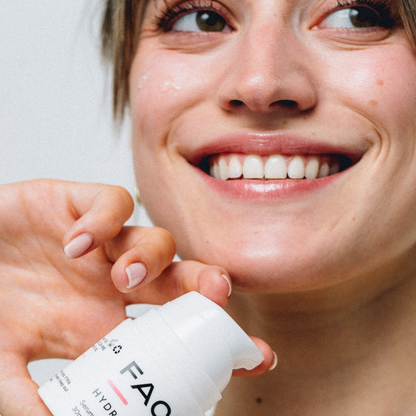 Woman applying skincare product to her face with a close-up of the bottle labeled 'FAO'.