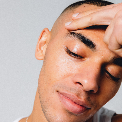 Man with hand on forehead against a plain background