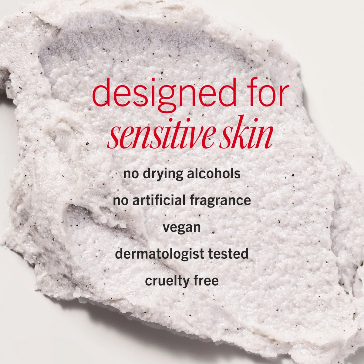 A close-up of a textured white exfoliating or cleansing scrub with black specks, overlaid with text reading 'designed for sensitive skin' and additional product claims on a light background.