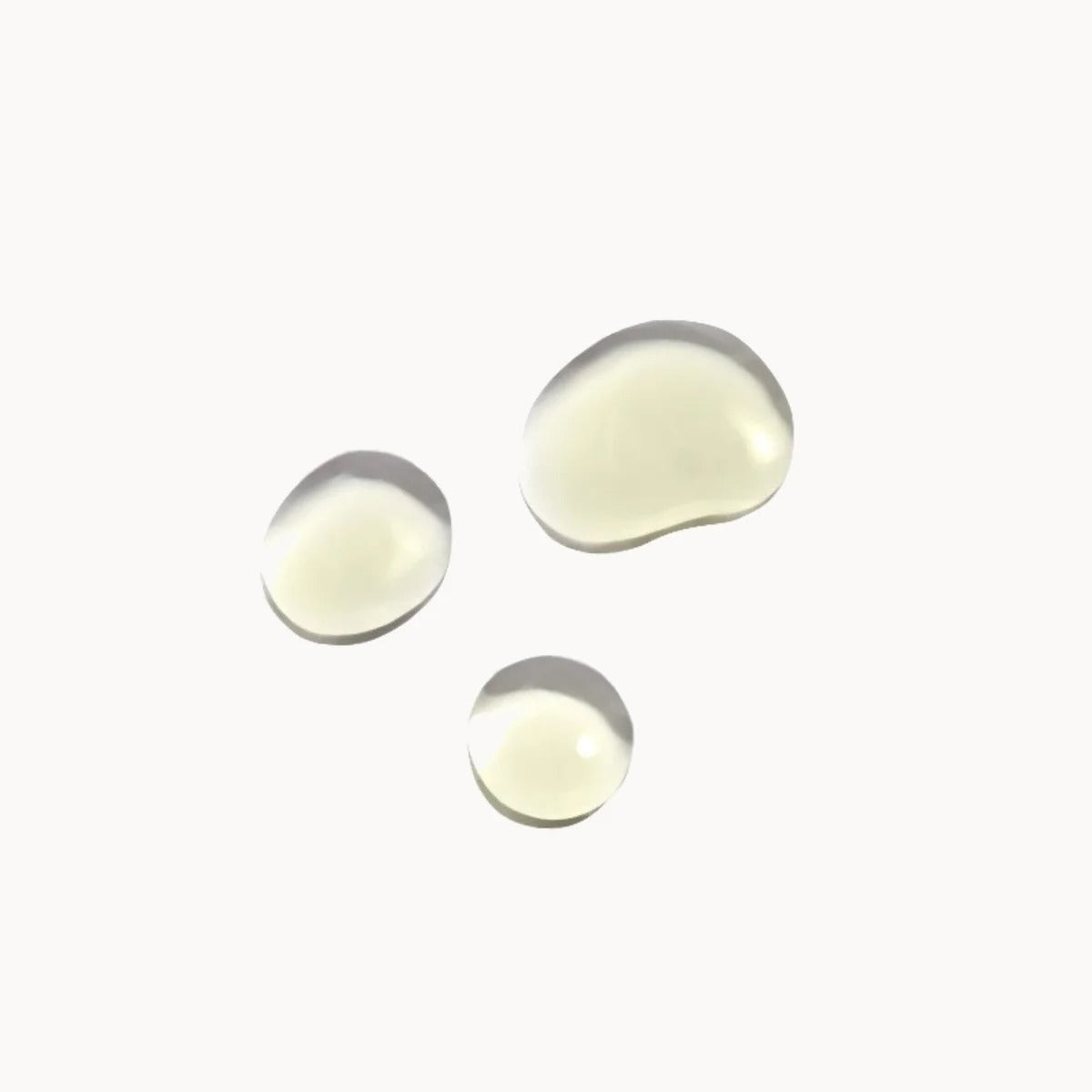 Three round, reflective droplets of Gallinee-Prebiotic-Face-Oil on a white background