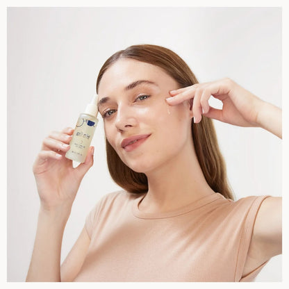 Woman applying skincare product to her face with a neutral background