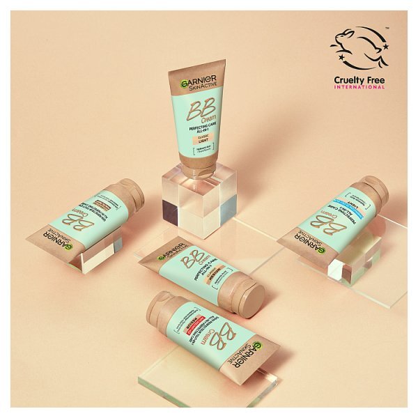 Four tubes of Garnier Instant BB Cream displayed on clear acrylic blocks against a warm beige background, with the Cruelty Free International logo in the top right corner.