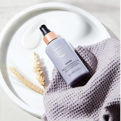 Haircare bottle labeled 'Glow' on a textured surface with a white plate and dried plant elements.