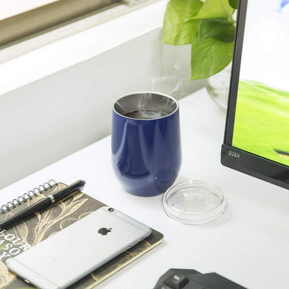 Blue mug with steam, smartphone, notebook, pen, and computer on a desk.