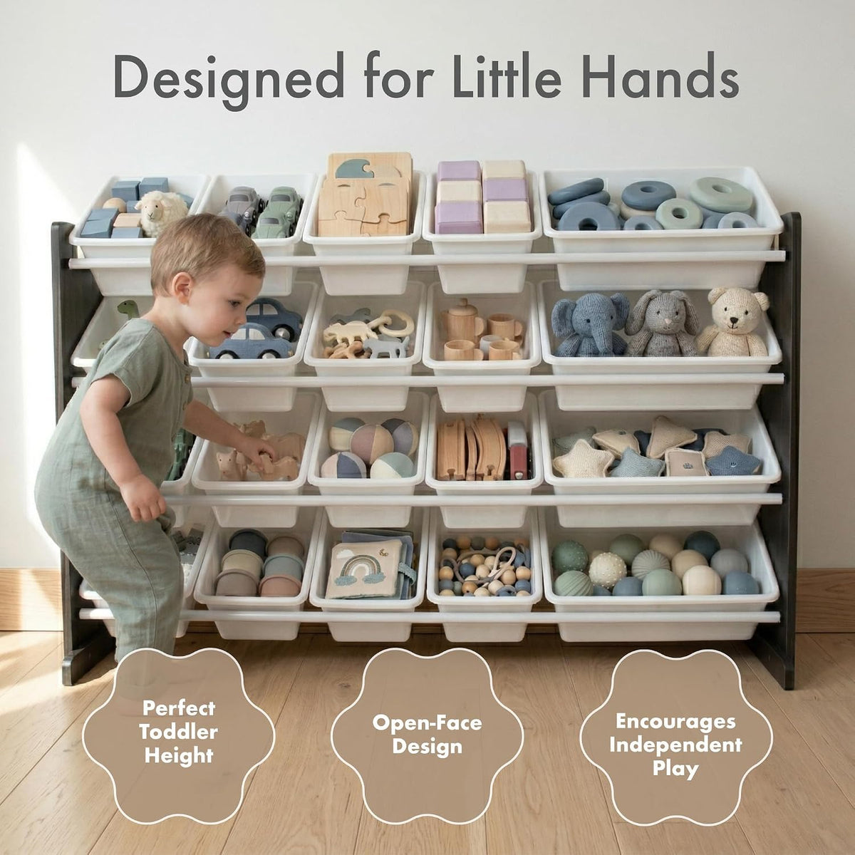 A toddler stands beside a freestanding open-bin toy organizer filled with wooden blocks, balls, stuffed animals, and puzzle pieces. Large text at the top reads 'Designed for Little Hands,' with three callout shapes at the bottom highlighting features like perfect toddler height, open-face design, and encouragement of independent play.