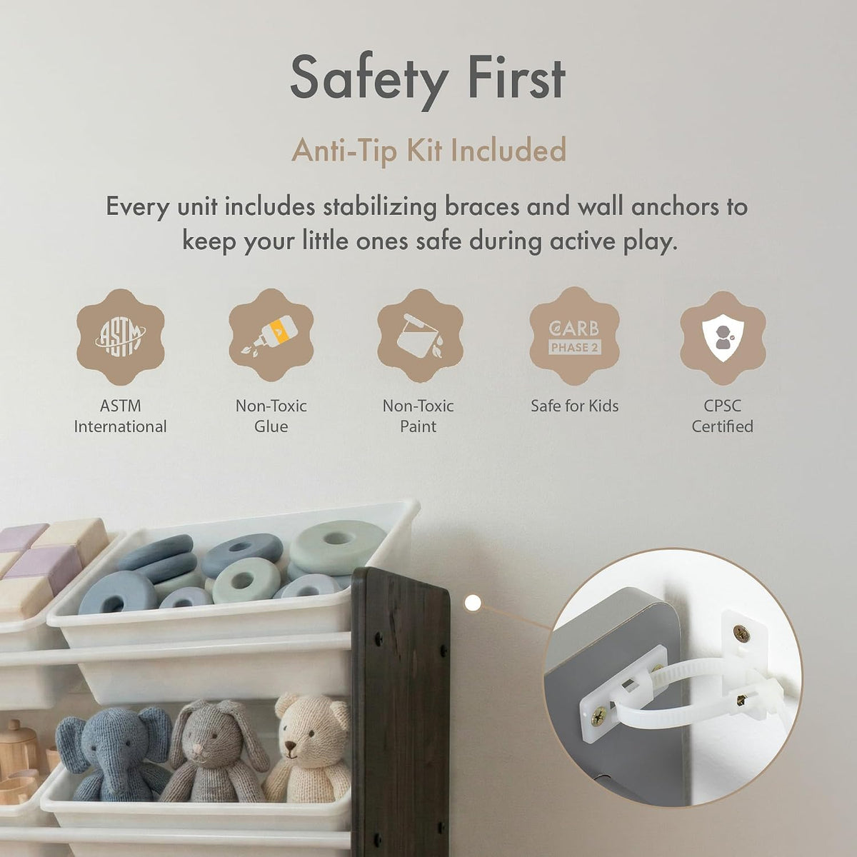 Safety First anti-tip kit for a children's toy shelf, featuring white plastic anti-tip brackets and anchors, shown with a wooden shelf holding stuffed toys and text detailing certifications and included accessories.
