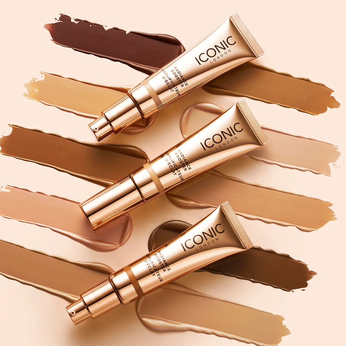 Three tubes of Iconic London foundation on a beige background with makeup swatches.