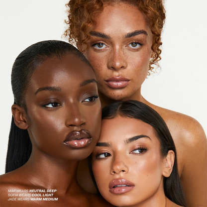 Three women with different skin tones posing together on a white background