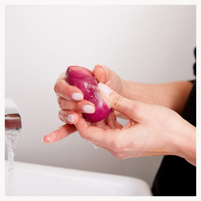 Person holding a pink make-up sponge against a white background