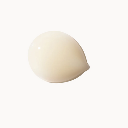 A single smooth, teardrop-shaped cream or gel droplet in a warm off-white or cream color, centered on a solid white background.