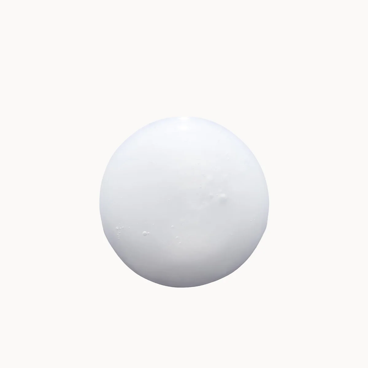 A single matte white spherical object centered on a plain off-white background.