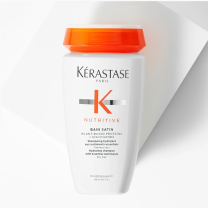 A white bottle of Kérastase Paris Bain 24/74 Nutritive shampoo with a bright orange cap, set against a clean white background with a diagonal shadow.