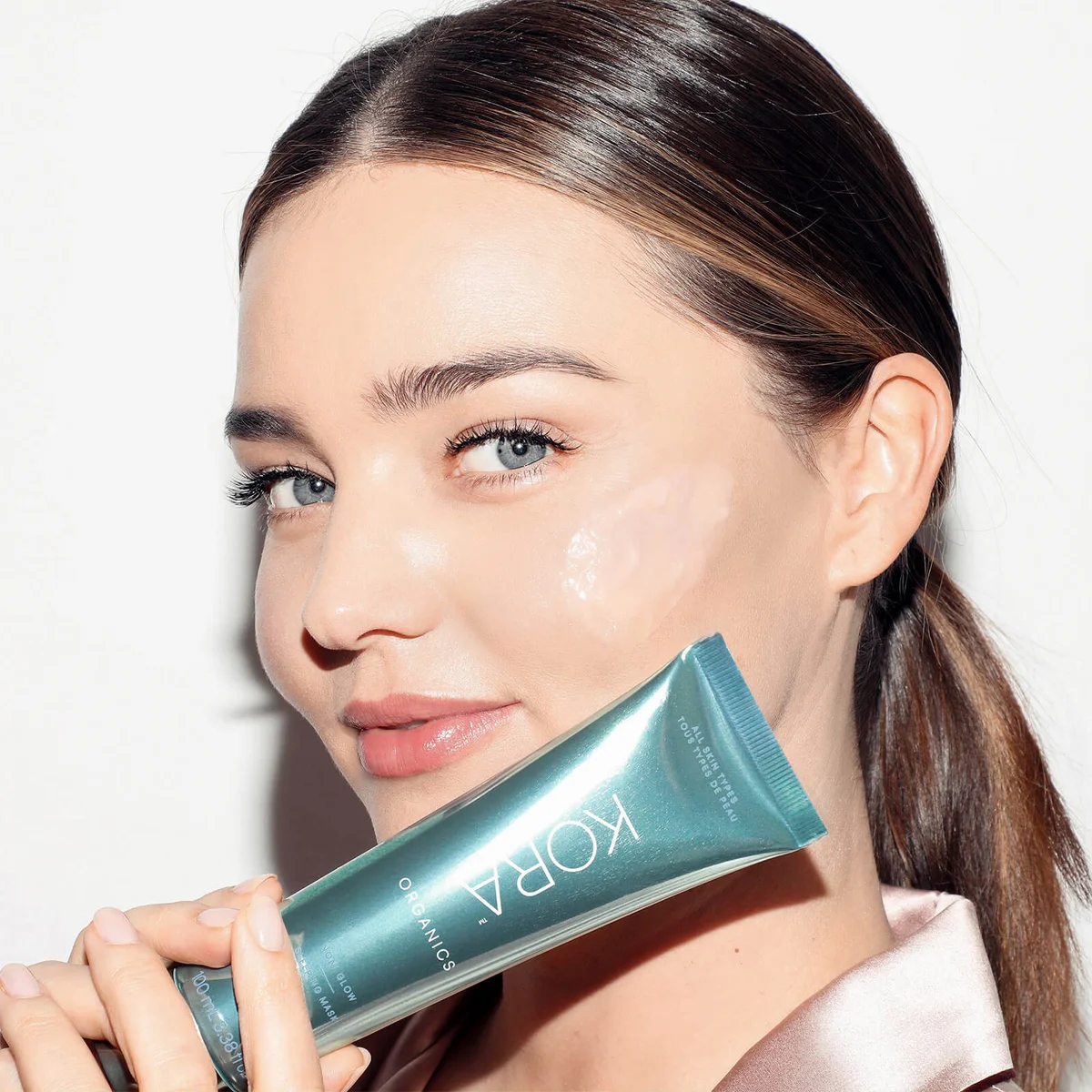 Woman holding a Kora Organics product against a white background