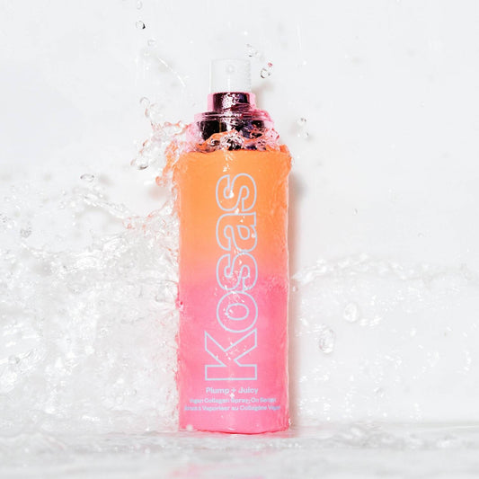A bottle of Kosas Plumage Spray standing upright in splashing water against a white background.