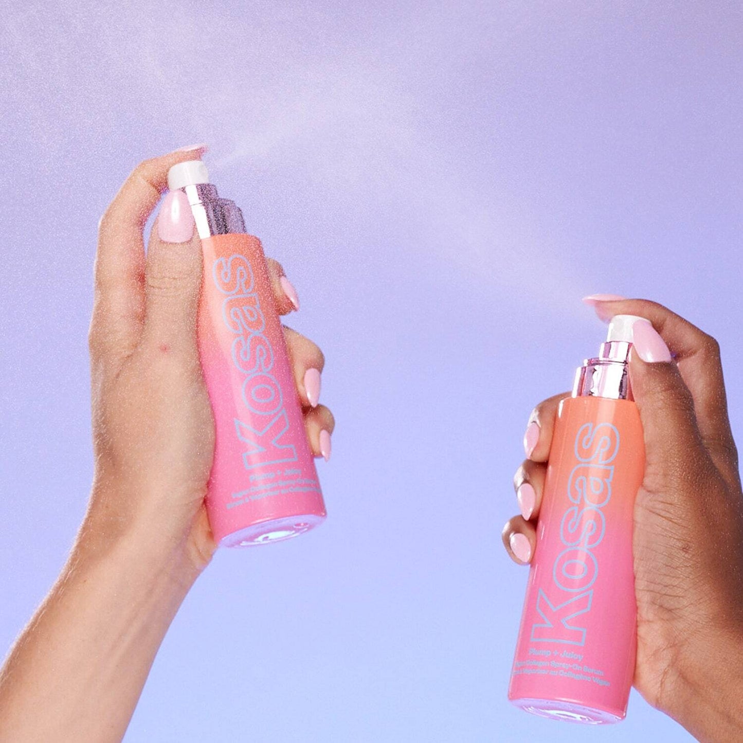 Two hands holding pink KIKOSAS spray bottles that are emitting a fine mist against a light purple background.