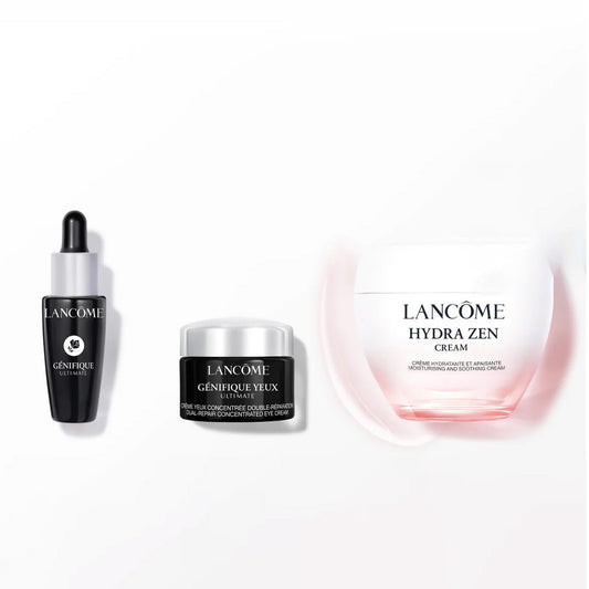Three Lancôme skincare products arranged on a white background: a black dropper bottle with a silver collar and black cap, a small black-and-silver jar, and a larger white jar with a pink glow around it. Visible text includes Lancôme, Hydra Zen, and Généfique.