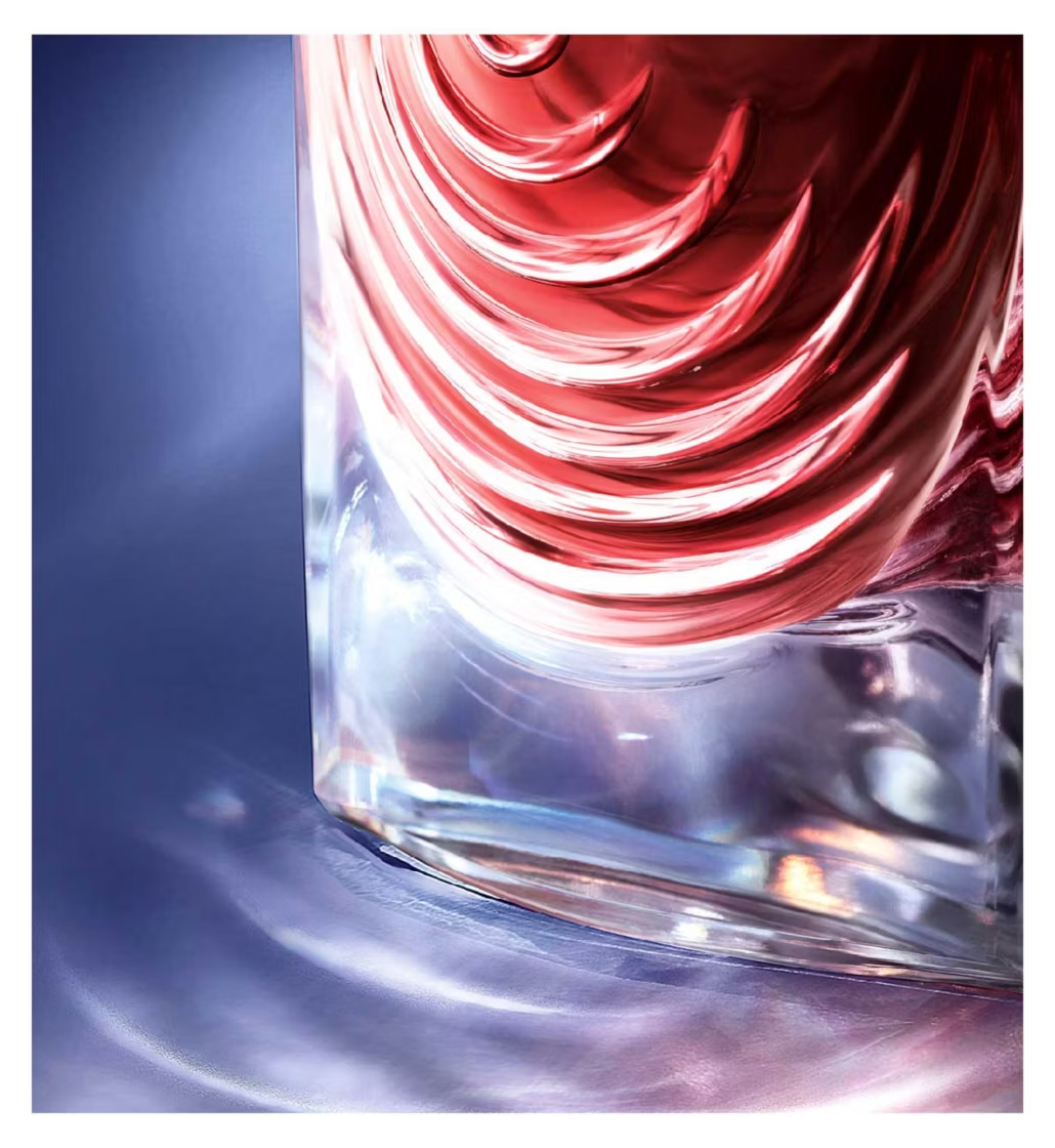 Close-up of a glass with red and clear liquid swirling inside on a blue background
