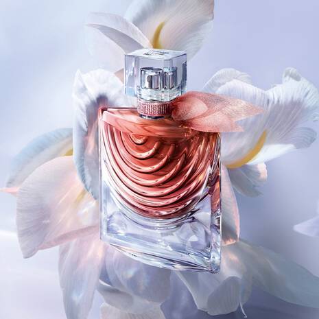 Perfume bottle with pink liquid on a white flower background