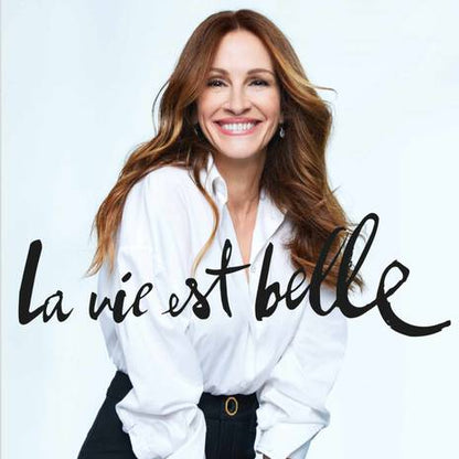 Actress Julia Roberts wearing a white shirt with 'La vie est belle' text on a light gray background