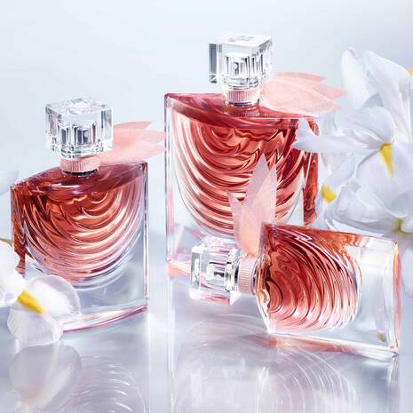 Three pink perfume bottles with floral design on a light background