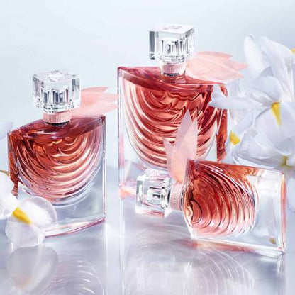 Three pink perfume bottles with floral design on a light background