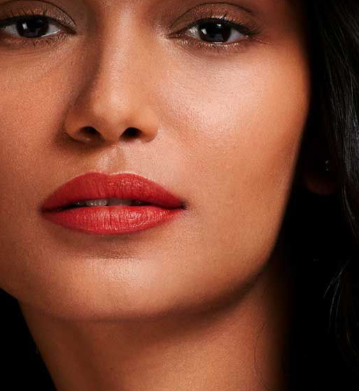 Close-up of a woman's face showcasing a vibrant matte red lipstick on her lips.