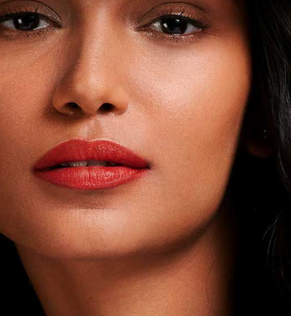 Close-up of a woman's face showcasing a vibrant matte red lipstick on her lips.