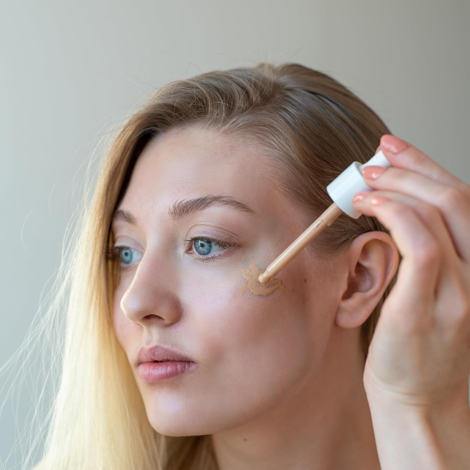 Woman applying cosmetic product to her face with a brush