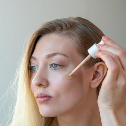 Woman applying cosmetic product to her face with a brush